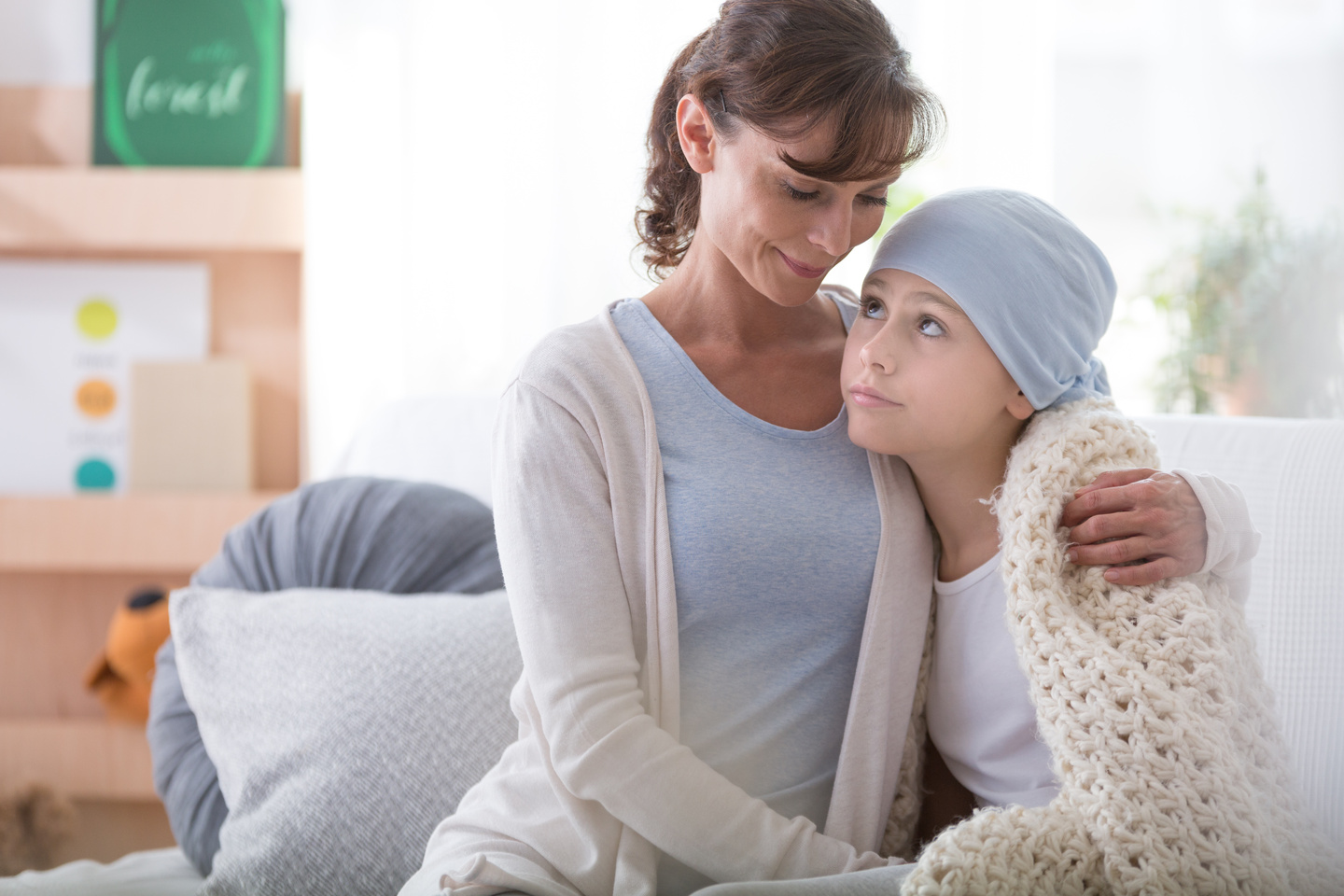 Smiling caregiver supporting sick child with cancer wearing blue headscarf Curso vacunas