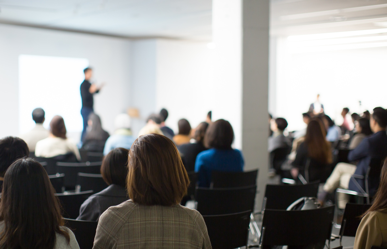 Presenter Presenting Presentation to Conference Audience. De-focused Blurred . Lecturer on Stage at Tech Forum. Speaker Giving Speech in Conference Hall Auditorium. Copy Space Screen Background. Equipo docente - Curso en Inmunización frente al SARS-COV2